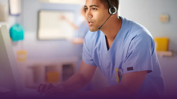 A male nurse working at his desk with a headset on